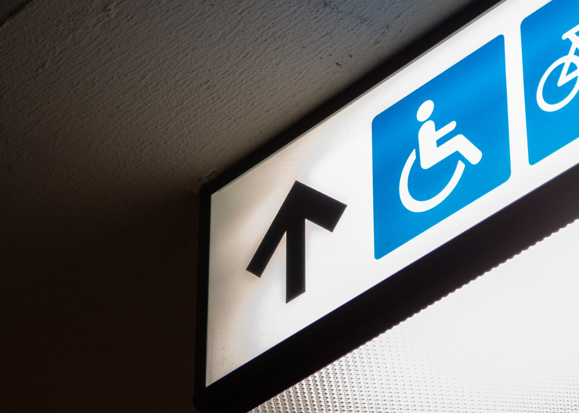Schild mit einem Pfeil und einem Symbol mit Rollstuhl und Person
