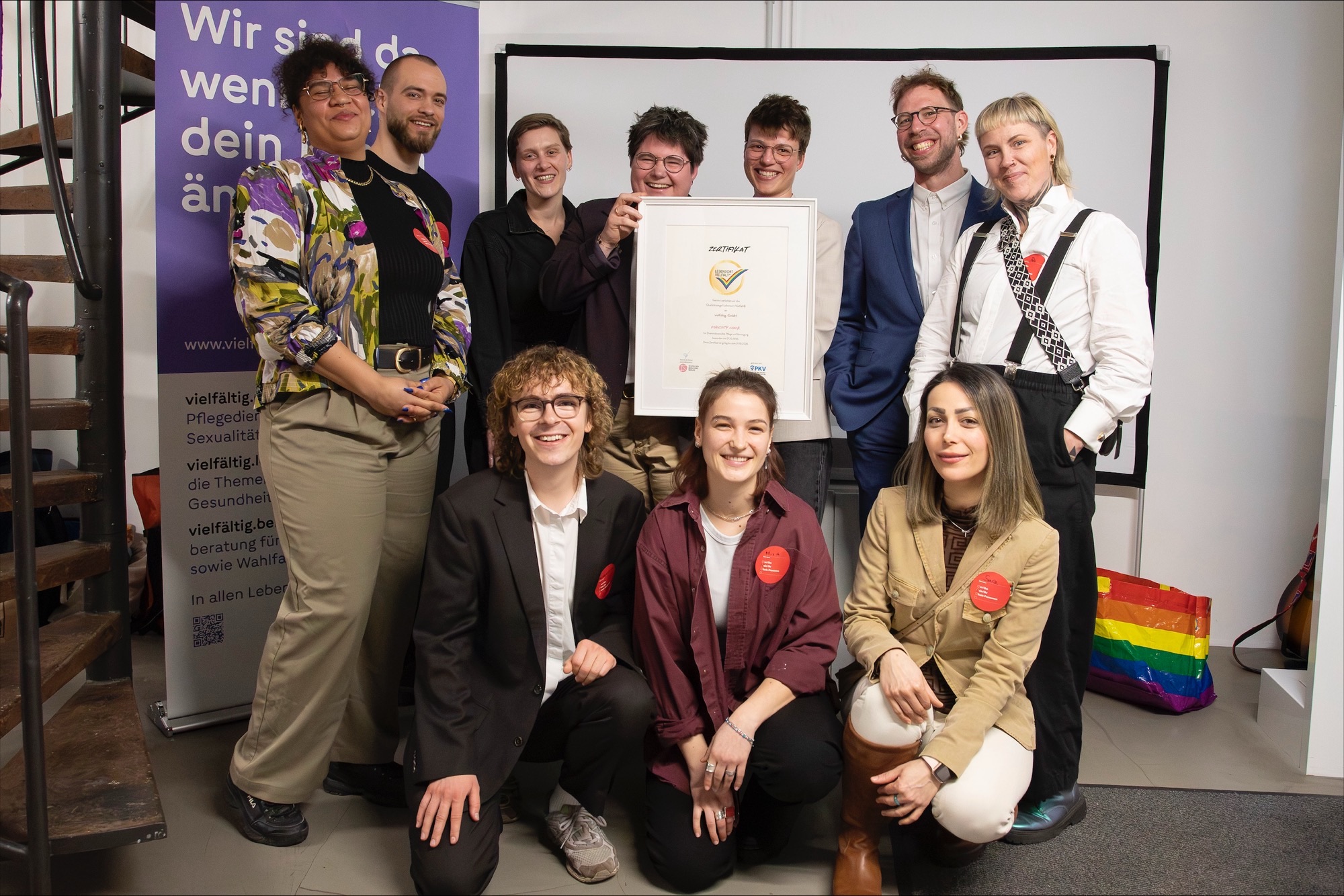 Das Foto zeigt 10 Personen mit einem Siegel im Bilderrahmen